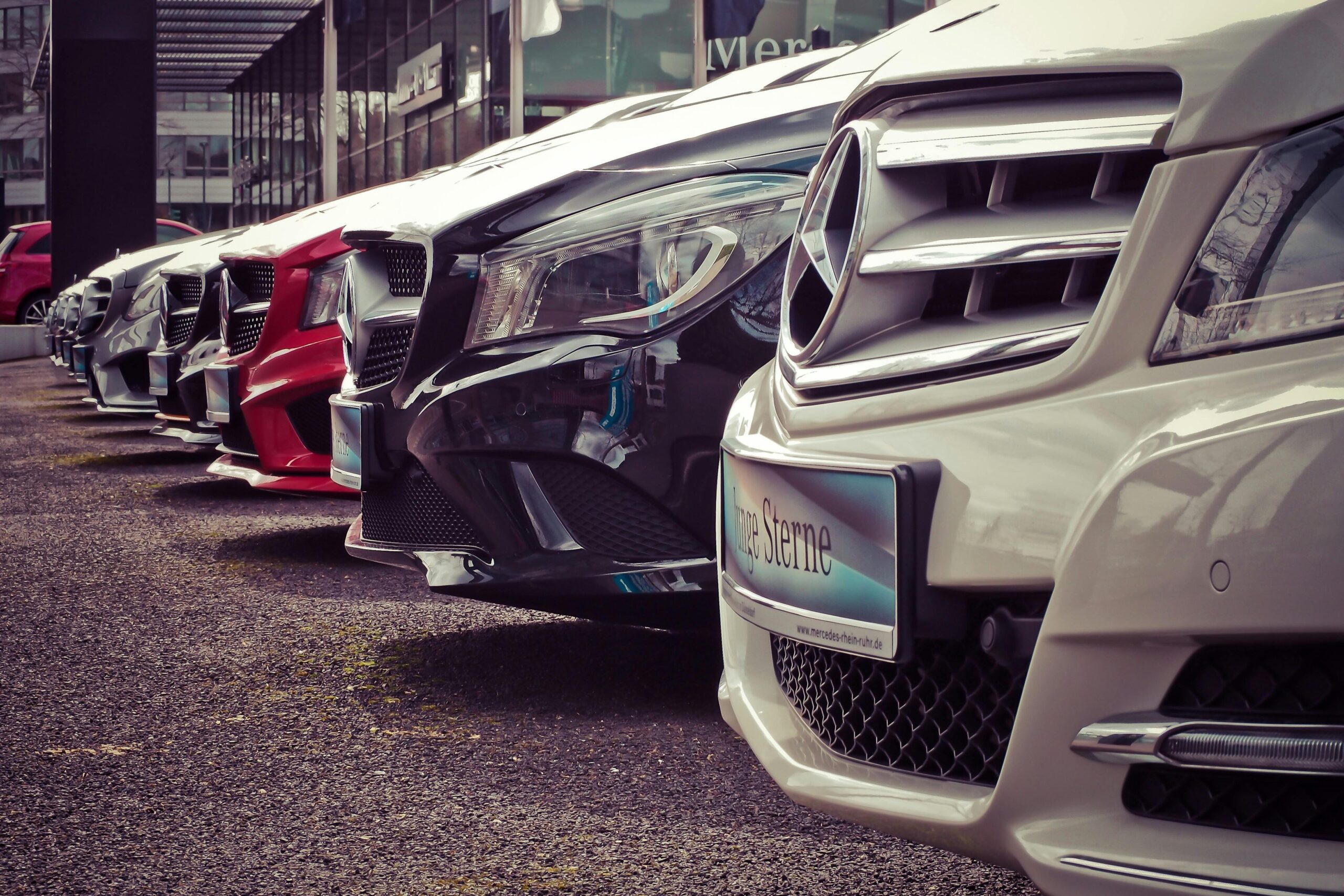 Luxury cars lined up at an outdoor dealership, showcasing sleek designs.